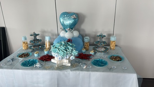 Mesa de bautizo en azul y blanco con globo y brochetas de chuches