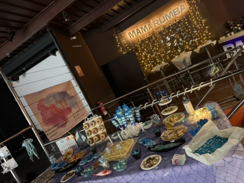 Mesa de cumpleaños de temática marina con dulces azules, tarta y barcos decorativos