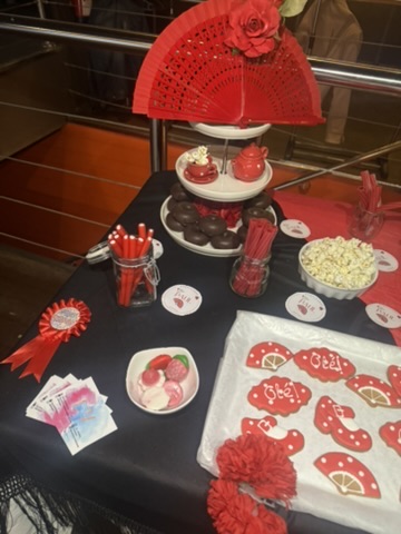 Mesa de fiesta en rojo y negro con abanico, flores y galletas decoradas