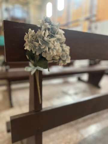 Ramo de hortensias con lazo decorando un banco de iglesia